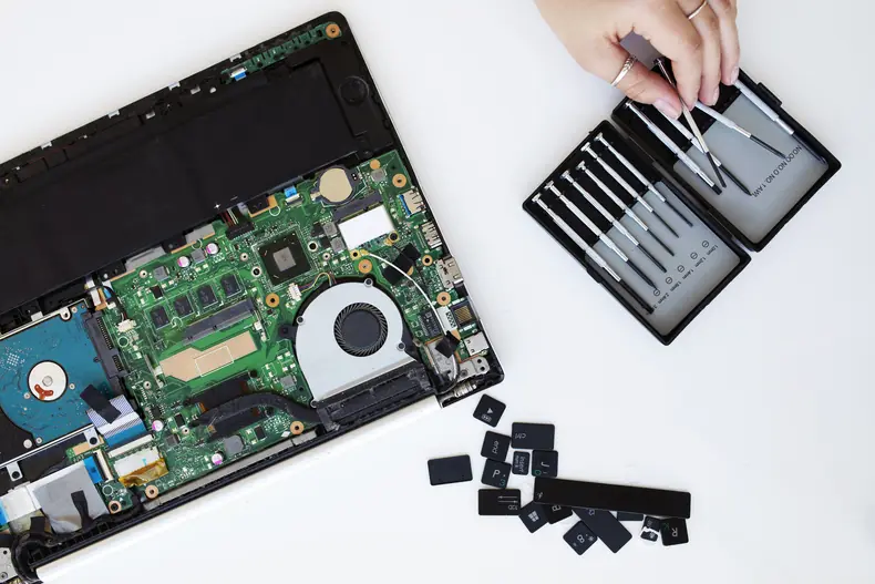 Notebook aberto na bancada de conserto com a placa-mãe à mostra