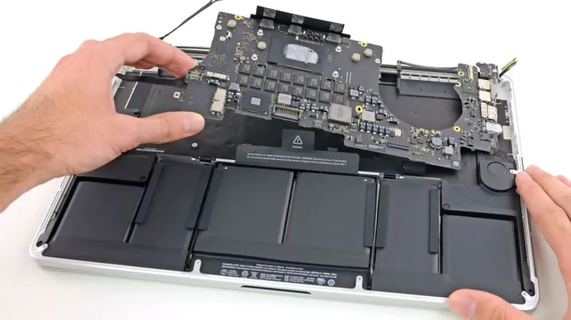 MacBook aberto com a bateria e a placa lógica expostas durante a manutenção