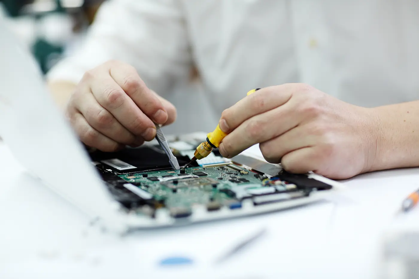 Técnico da Magitronic fazendo reparo com ferro de solda na placa de um notebook